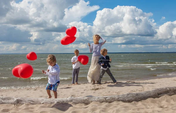 Madre joven y tres niños con globos rojos — Foto de Stock