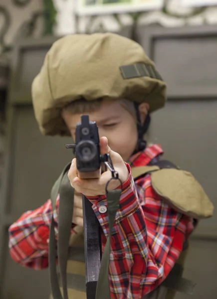 Мальчик в военной форме с винтовкой прицеливается. — стоковое фото