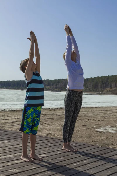 Jovem mulher e menino praticando ioga — Fotografia de Stock