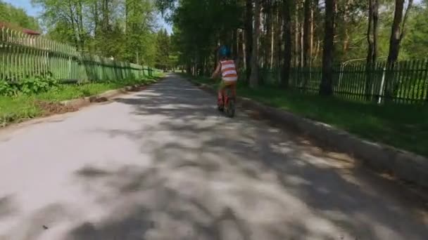 Счастливый ребенок катается на велосипеде по дороге в пригороде . — стоковое видео