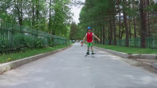 Мальчик катается на роликах по дороге — стоковое видео