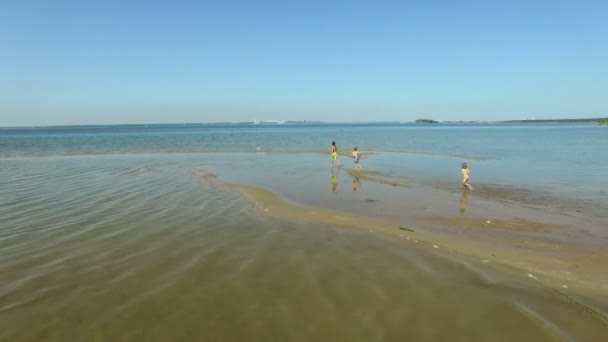 Tre barn som kör ner till stranden i soliga dag. — Stockvideo