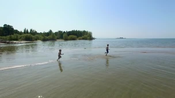 Два счастливых мальчика бегут по пляжу в солнечный день . — стоковое видео