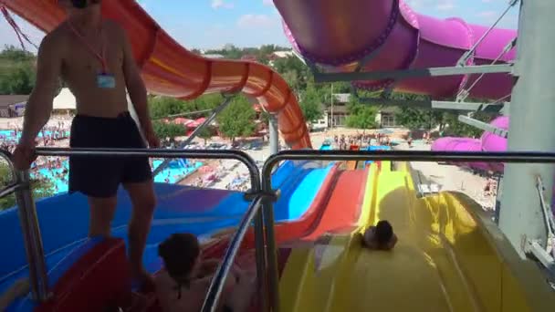 Pessoas deslizando de grande corrediça de água colorida em aquapark grande — Vídeo de Stock