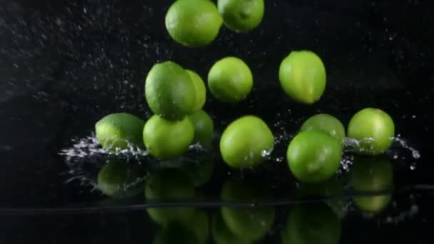 Limas cayendo con agua sobre fondo negro — Vídeo de stock