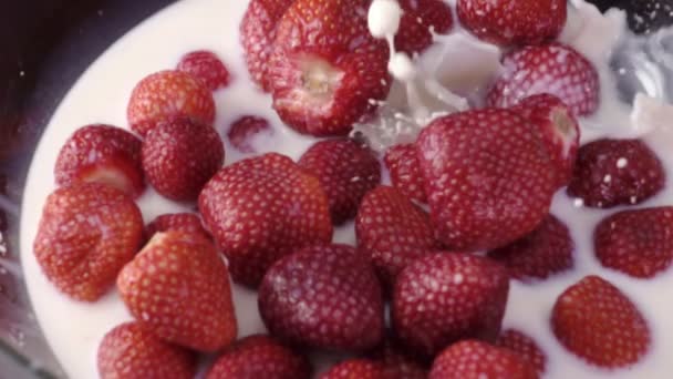 Leche vertiendo en un tazón con fresas frescas en cámara lenta — Vídeos de Stock