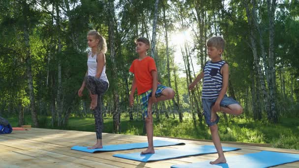 Young woman and kids performing yoga — Stock Video