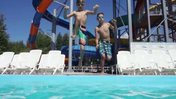 男孩们一起跳入蓝池水向镜头 做了很多飞溅 慢动作的射击 — 图库视频影像