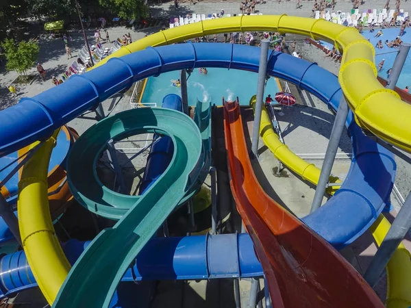 Water slides in aqua park at large outdoor swimming pool in summer sunny day