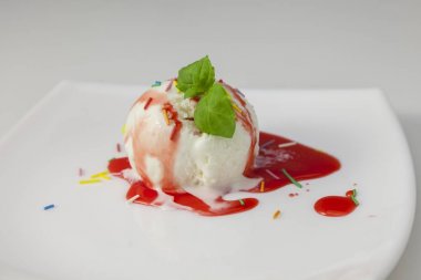 çilek sosu ve nane beyaz plaka üzerinde vanilyalı dondurma topla