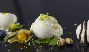 Dondurma kaşık toz meyveler, fındık ve siyah arka plan üzerine nane dekorasyon ile ayarla.