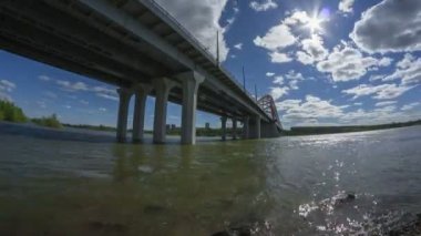 Timelapse görünümü güzel bulutlar mavi gök, güneş parlıyor. Asma köprü Bugrinsky Novosibirsk, Sibirya, Rusya güneşli gün zaman atlamalı Ob Nehri üzerinde.