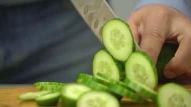 erkek ellerini tutarak keskin bıçak ve ahşap tahta üzerinde taze salatalık doğrama