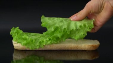 marul yaprakları ve siyah arka plan üzerine jambon ile taze denizaltı sandviç hazırlama