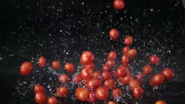 Zeitlupe Kirschtomaten Fallen Wasser Mit Spritzern Zeitlupe Auf Schwarzer Oberfläche — Stockvideo