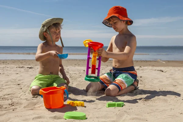 Kids play with sand on beach in sunny day. Summer vacations concept.