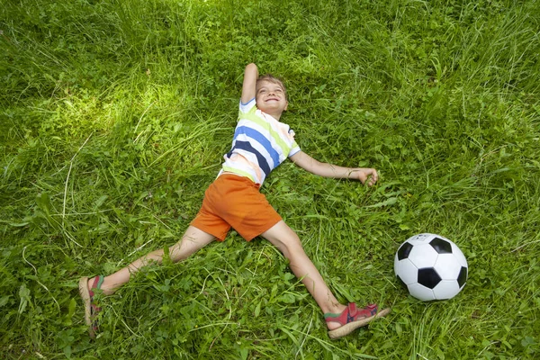 Niño Feliz Acostado Hierba Verde Patear Pelota Fútbol Día Soleado — Foto de Stock