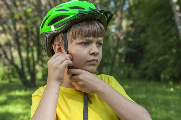 晴れた日にサイクルのためのヘルメットを着用少年 子供たちはサイクリングを開始するために自転車のヘルメットを着用して準備 ストック写真