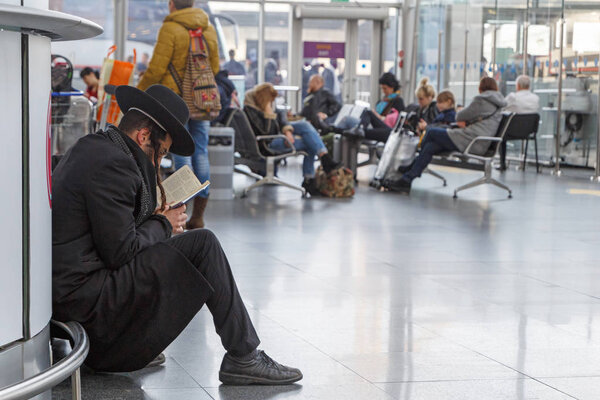 КИЕВ, УКРАИНА - 11 марта 2018 года: Еврей читает Тору на полу аэропорта Борисполь в Киеве, Украина
