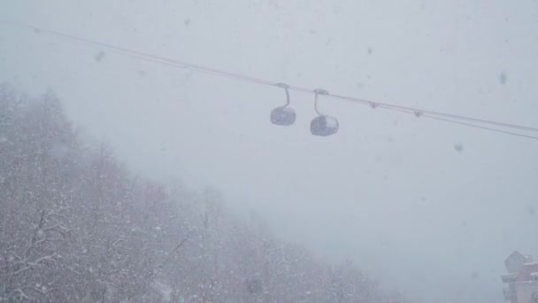 Kayak merkezi eğlenceleri. Gondol kabin asansörünün altında. Gondol kablosu. Sisli kar yağışı altında teleferik kaldırışı. Kar tanelerinin arka planında teleferik kaldırma. Toz günü. Kış Döngüsü Yavaş Hareketi — Stok video