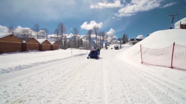 Vrienden hebben plezier op het skigebied. Jonge glimlachende mensen op een sneeuwscooter. Drie personen op een sneeuwscooter genieten van de winterdag. — Stockvideo