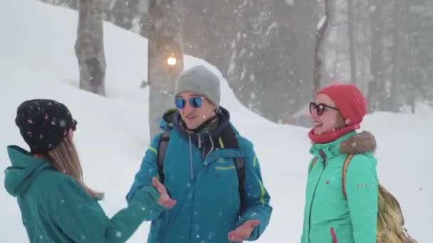 Los amigos se divierten en la estación de esquí. Compañía de amigos divirtiéndose de vacaciones en las montañas de invierno. Un chico y dos chicas disfrutan del invierno en la estación de esquí . — Vídeos de Stock