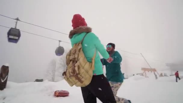 Друзья веселятся на лыжном курорте. Компания друзей веселится на отдыхе в зимних горах. Две девушки наслаждаются снежным днем на горнолыжном курорте. Девушки держатся за руки и крутятся  . — стоковое видео