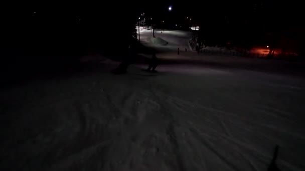 Två kvinnliga snowboardåkare har en lång kväll snowboard. Flickor ha kul på natten på skidorten. Flickor upplever natten ridning på tom stig. — Stockvideo