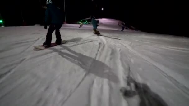 Arkadaşlar kış sporlarının tadını birlikte çıkarıyorlar. Gece gökyüzünün altında iki arkadaş senkronize snowboard yapıyor. Kış Maceraları. — Stok video
