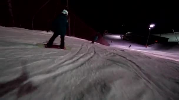 Mladá dívka zažívá snowboard freestyle. Jízda v noci na lyžařském středisku. Jízda pod noční oblohou — Stock video