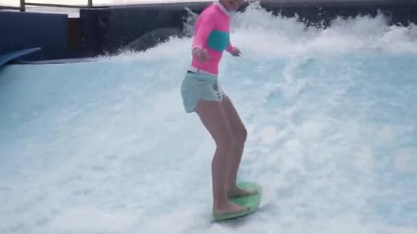 Young woman FlowRider and flow board on artificial sheet waves. The water flows up and over surfaces engineered to replicate the shape of ocean waves. A young woman falling expression funny on the — Stock Video