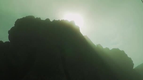 Die Morgensonne steigt durch felsige Gipfel. nebliges Morgenlicht. Abenteuertourismus. — Stockvideo