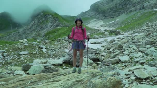 Wandermädchen in den atemberaubenden nebligen Frühlingsbergen. Eine Wanderung mit Wanderstöcken. Mädchen in bunten Wanderkleidern halten Trekkingstöcke in den Bergen. — Stockvideo