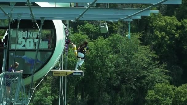 207 metre yüksekte bungee jumping yapıyor. Kız geriye doğru sıçramış. Ağır çekim. Kız selfie çekip bungee atlayışı yapıyor. — Stok video