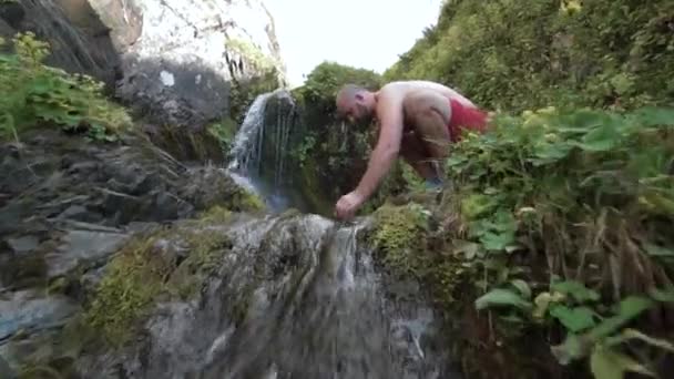 Close Up, Slow Motion: Vandrare stannar för att tvätta ansiktet med det glasartade flodvattnet en solig sommardag. En kille som svalkar sig i ansiktet — Stockvideo