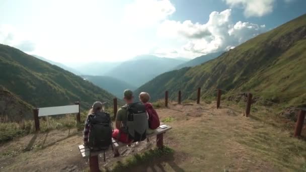 Giovani escursionisti che si rilassano sulla panchina, vista panoramica. Giovani escursionisti che si rilassano sulla panca di legno dalla cima della montagna . — Video Stock
