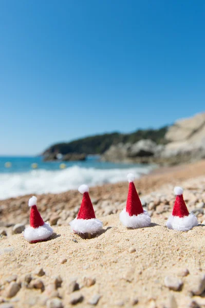 Hüte des Weihnachtsmannes am Strand — Stockfoto