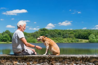 Senior man with old dog in nature landscape clipart