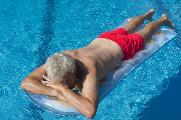 Senior man drijvend op het water — Stockfoto