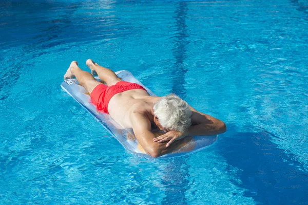 Senior man drijvend op het water — Stockfoto