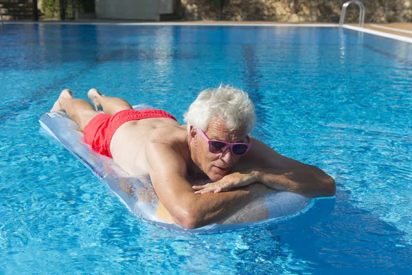 Senior man drijvend op het water — Stockfoto