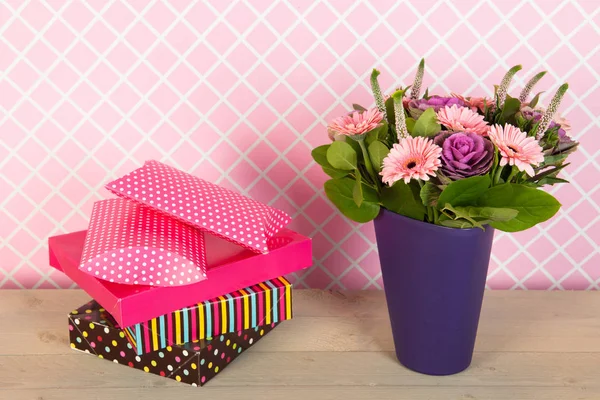 Flores de buquê coloridas em vaso azul e presentes embrulhados — Fotografia de Stock