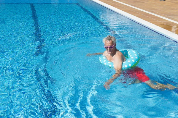 Senior man on vacation in swimming pool — Stock Photo, Image