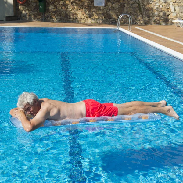 Senior man drijvend op het water — Stockfoto