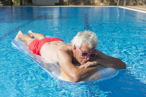 Senior man drijvend op het water — Stockfoto