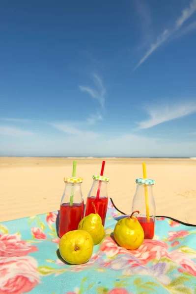 Bottles lemonade and fruit at beach — Stock Photo, Image