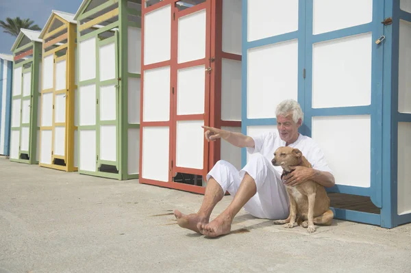 Colorful beach huts and senior man with dog — Stock Photo, Image