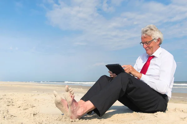 Biznes człowiek działa na tablecie na plaży — Zdjęcie stockowe