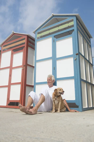 Barevné plážové chatky a starší muž se psem — Stock fotografie