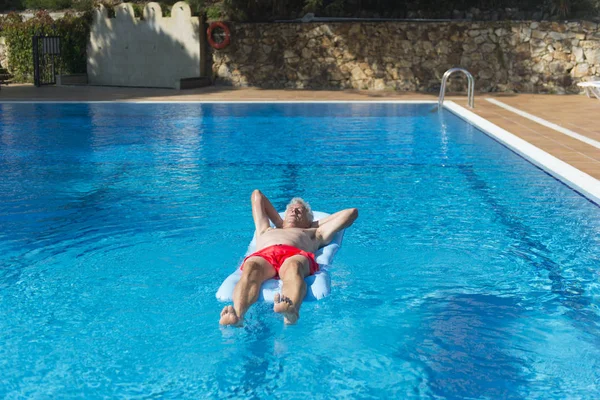 Senior man floating on water — Stock Photo, Image